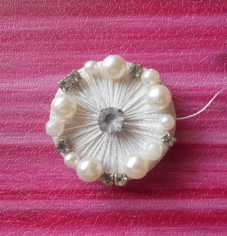 Adding pearls to the brooch.