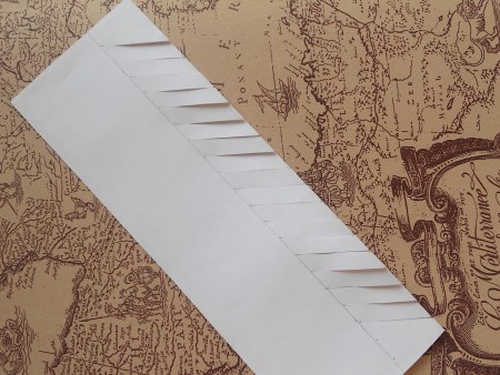 Making diagonal cuts along the side of the folded paper.