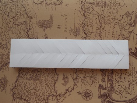 Refolding the paper so the diagonal cuts make an arrow shape.