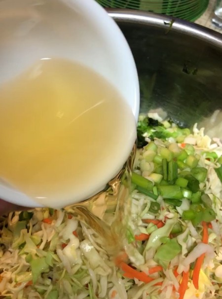 Adding dressing to the cole slaw.