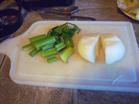 Onion and celery on a cutting board.