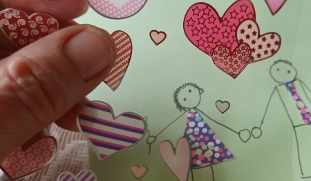 Adding heart stickers to a card.