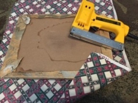 Stapling the fabric to the underside of a seat.