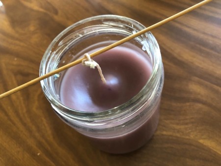 Using a stick to keep the wick straight.