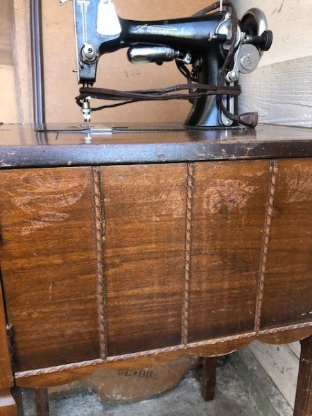 An antique sewing machine on a wooden stand.