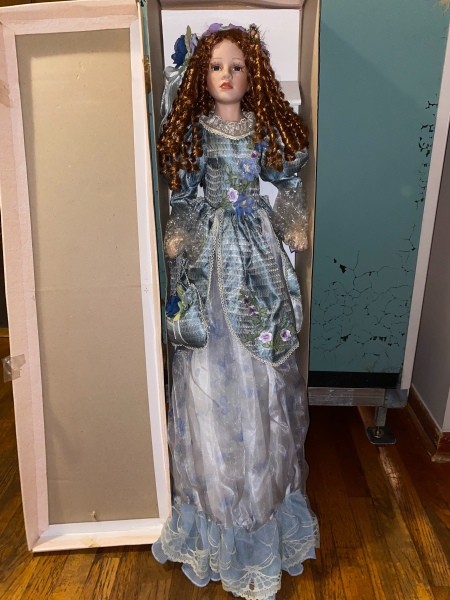 A porcelain doll next to it's box.