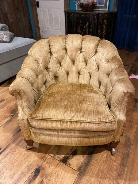 An armchair upholstered in tan velvet.