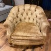 An armchair upholstered in tan velvet.