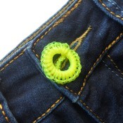 The crocheted fishing line button on a pair of jeans.