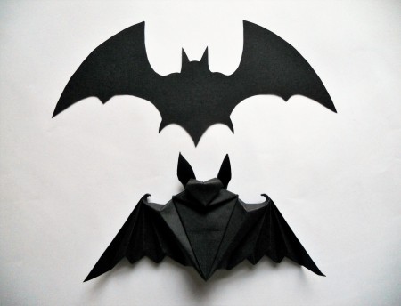 A bat silhouette next to an origami bat.