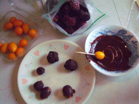Dipping kumquats in the melted dark chocolate.