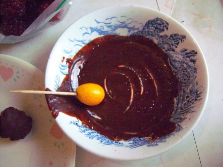 Dipping kumquats in the melted dark chocolate.