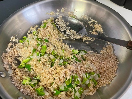 Adding vegetables to the rice mixture.