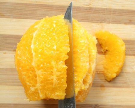 Cutting the orange into sections.