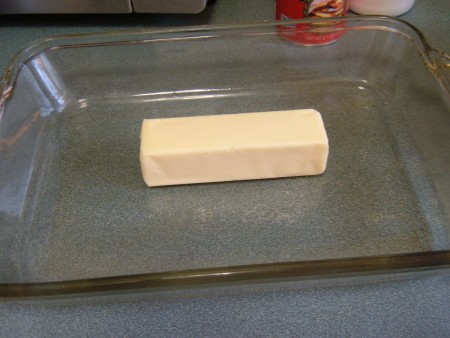 A stick of butter in a baking pan.