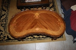 A wooden coffee table with inlays and carved sides.