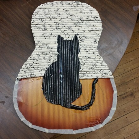 Adding the rolls to a recycled guitar, with a black cat pattern in the center.