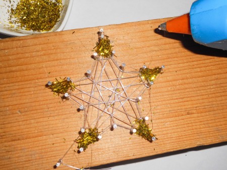 Adding glue and glitter to the star's corners.