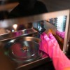 A gloved hand cleaning a microwave oven.