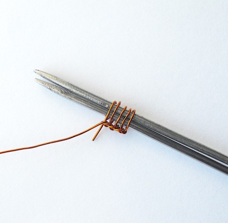Wrapping wire around knitting needles.