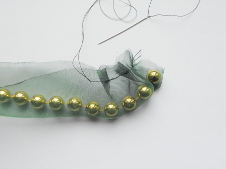 Sewing a string of beads inside the folded organza.