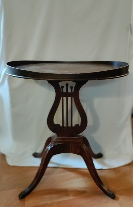 A round wooden table with a lyre design.