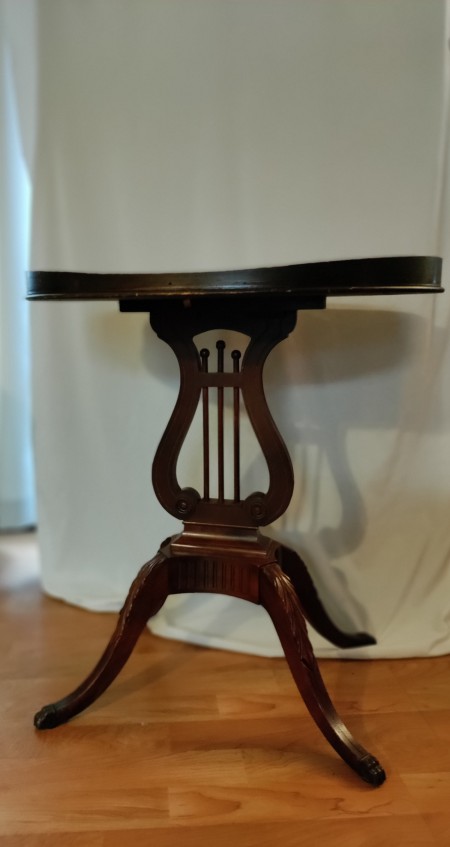 A round wooden table with a lyre design.