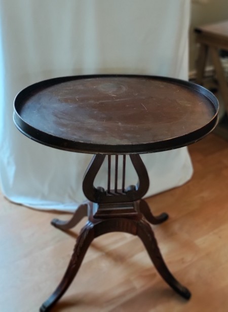 A round wooden table with a lyre design.