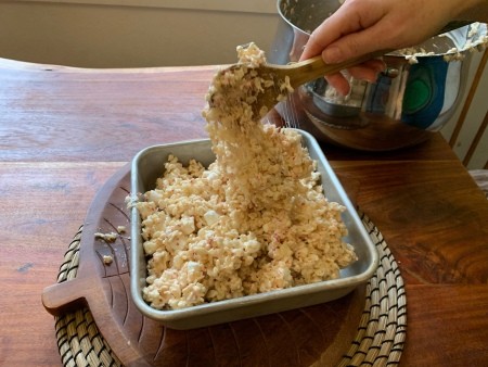 Adding the rice krispies to a square pan.