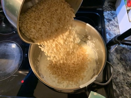 Adding rice krispies to the melted marshmallows.
