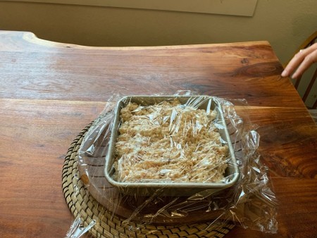 Covering the pan with plastic wrap.
