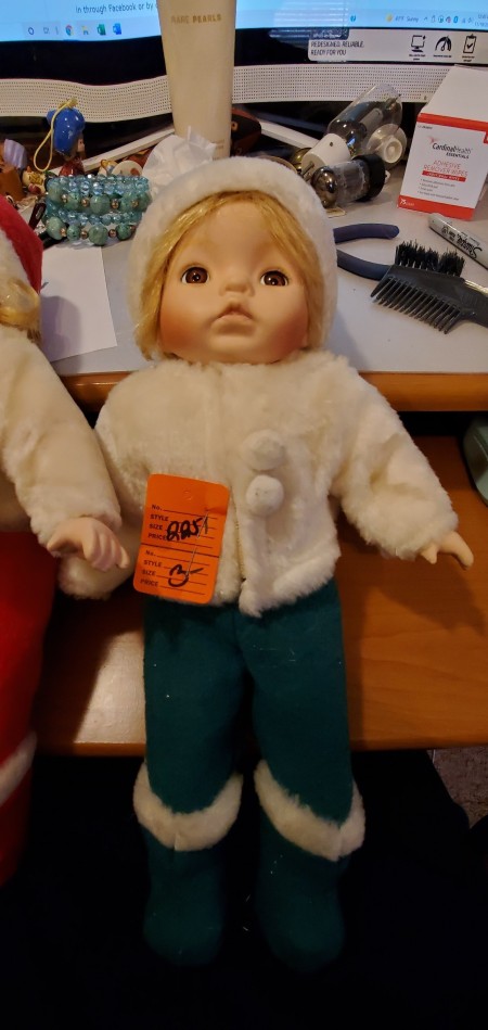 A small blonde doll in winter clothing.