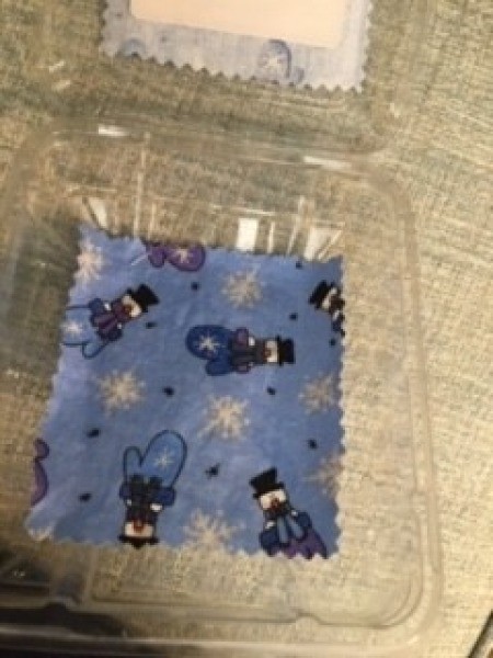 Attaching the fabric to the top of the recycled plastic container.