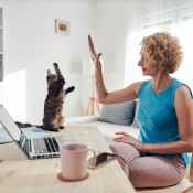 A woman working at home giving a high-five to her cat.