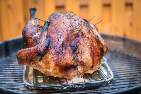 A turkey being cooked on a barbecue.