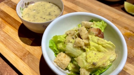 A bowl of salad with vegan caesar dressing.