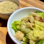 A bowl of salad with vegan caesar dressing.