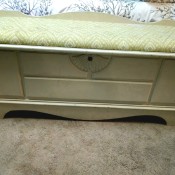 A light colored cedar chest with a cushion on top.