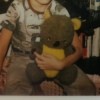 An old stuffed bear in a boy's arms.