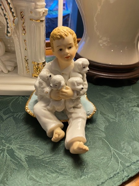 A figurine of a child holding 4 puppies.