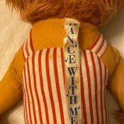 The "Dance with Me" tag on the stuffed toy.