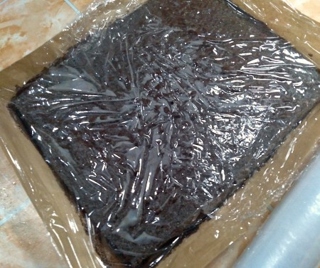 Covering the cake in plastic wrap.