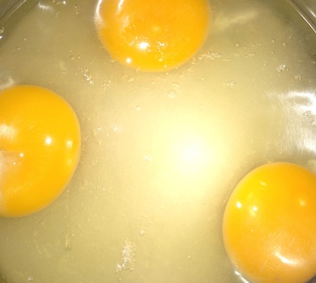 Cracking eggs into the saucepan.