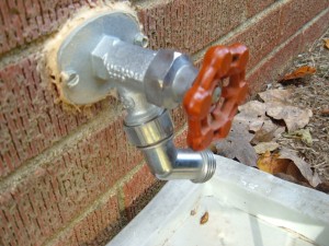 An outdoor faucet on a brick wall.