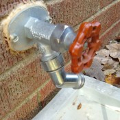 An outdoor faucet on a brick wall.