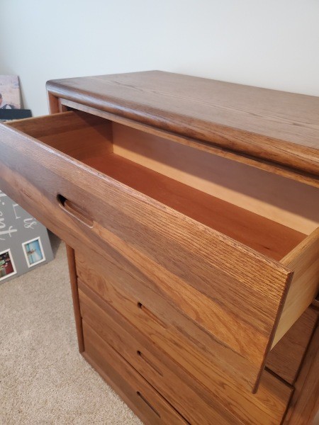 A wooden dresser with the top drawer open.