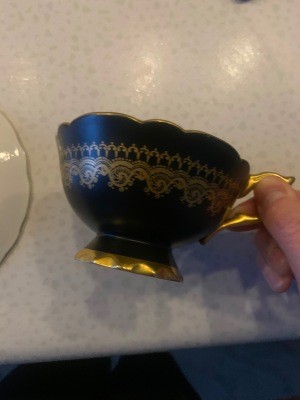 A matte black tea cup with gold decorations.
