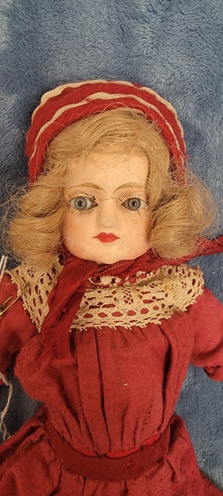 An old doll wearing a red dress.