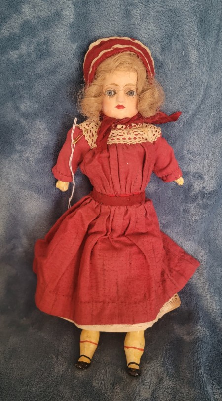 An old doll wearing a red dress.