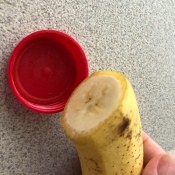 A cut banana next to a lid to fit.